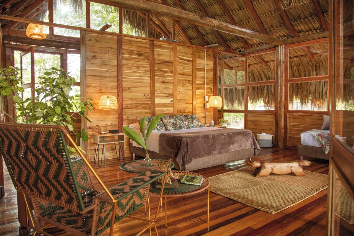 Ein Holzblockhaus-Interieur mit Bett, Sitzecke und großen Fenstern.