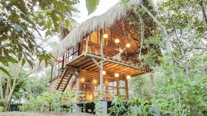 A wooden cabin with a thatched roof, surrounded by lush greenery. - Hacienda Boutique  (Restrepo)