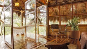 A spacious room with wooden floors, large windows, and a thatched roof. - Hacienda Boutique  (Restrepo)