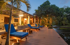 A wooden deck with lounge chairs and tables, a pool, and a river in the background. - Hacienda Boutique  (Restrepo)