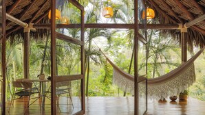 A wooden deck with a hammock, a table, and chairs, overlooking a lush tropical garden. - Hacienda Boutique  (Restrepo)
