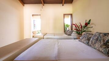 Cozy retreat with a large bed, small table, and potted plant.