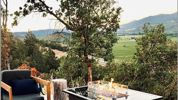 An outdoor patio with a foosball table, wooden furniture, and a view of the countryside.