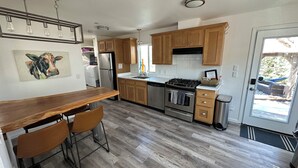 A modern kitchen with wooden cabinets, stainless steel appliances, a bar area, and a view of the outdoors.