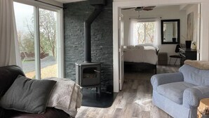 A modern living room with a stone fireplace, a large window, and a cozy seating area.