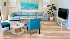 A living room with a sofa, a coffee table, a chair, a TV stand, and a potted plant. - Monthly Coastal Stay - Fully Furnished 3BR/2BA Home (Oceanside)