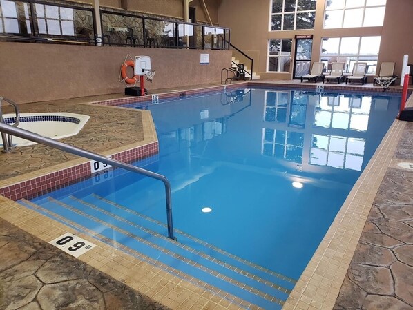 Una piscina interior con agua cristalina, marcas de profundidad y un flotador.