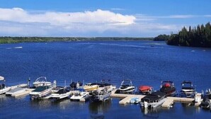 A marina with boats docked, calm water, and a clear sky.