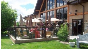 A building with large windows and a covered outdoor seating area with umbrellas.