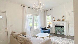 A living room with a sofa, a small round table, a blue chair, a chandelier, and a fireplace. - House - Wetumpka (Wetumpka)