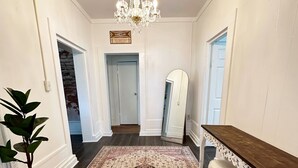 A hallway with a chandelier, a large rug, a plant, and a mirror. - House - Wetumpka (Wetumpka)