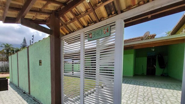 A covered outdoor area with a metal gate, a tiled floor, and a green wall.