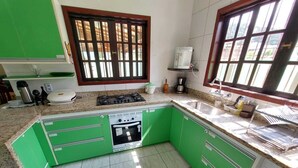 A kitchen with green cabinets, a gas stove, a built-in oven, a sink, and a window with bars.