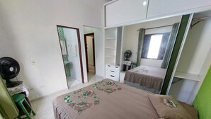 A bedroom with a bed, a desk, a chair, a mirror, and a wardrobe.