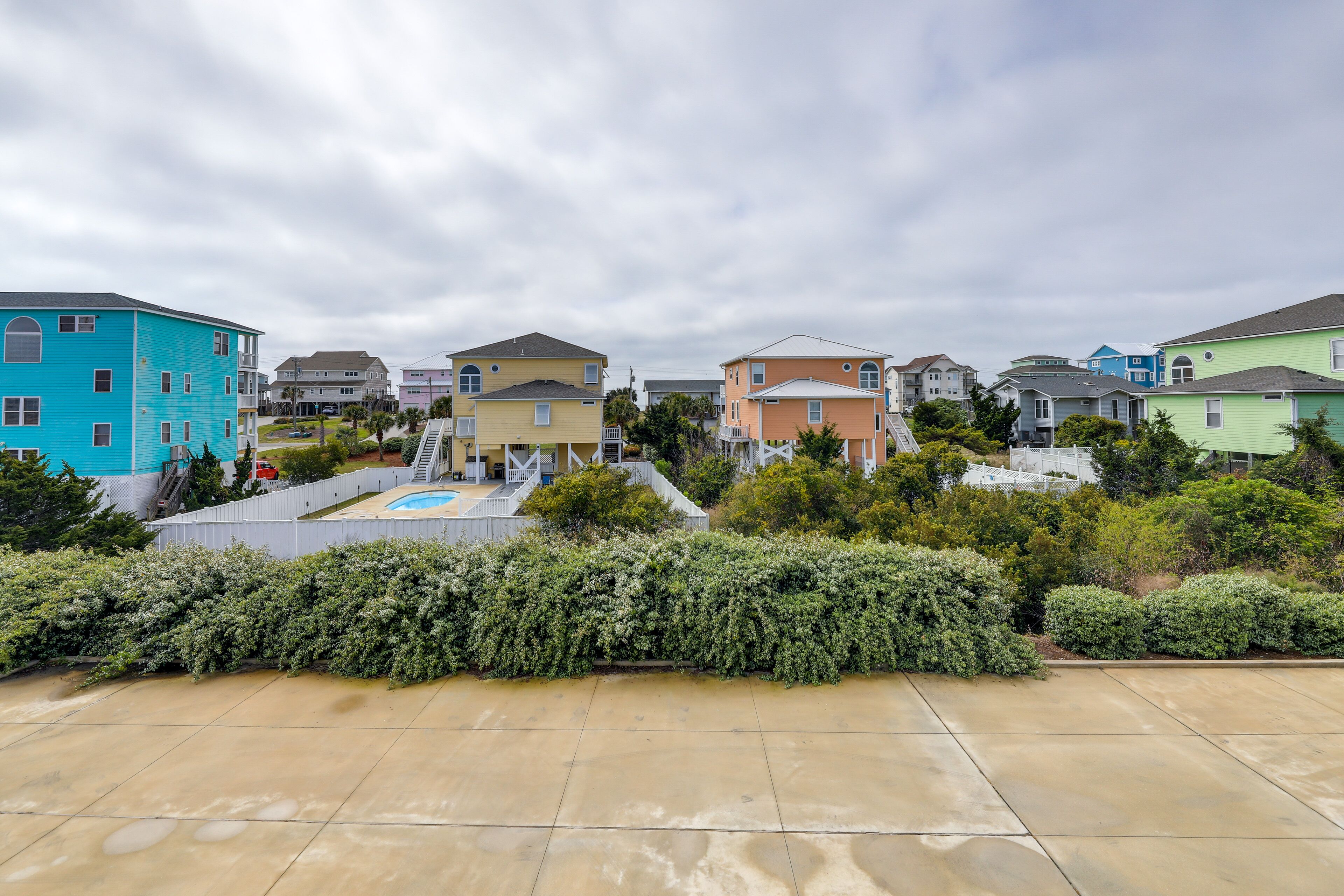 Un quartier résidentiel avec des maisons aux couleurs vives, une piscine et un jardin bien entretenu.