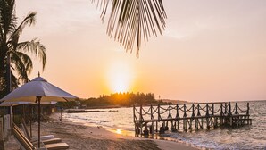 A beach with a wooden pier extending into the water, a row of beach chairs, and a palm tree. - Marine Beach Club & Hotel By Tequendama (Cartagena)