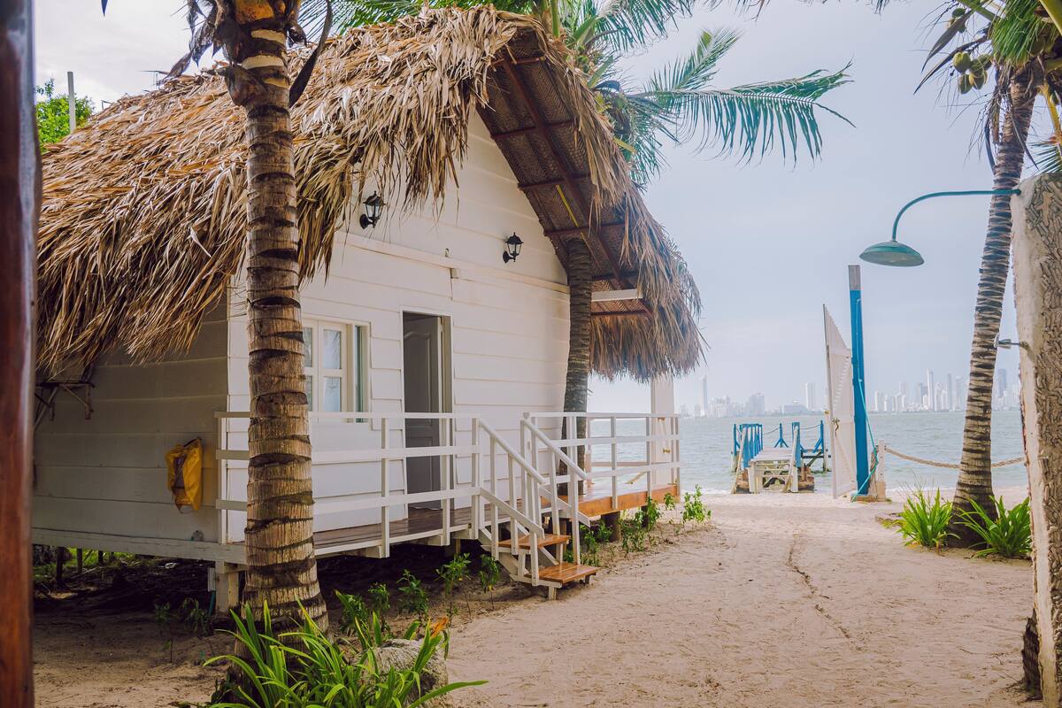 A beachside building with a thatched roof, a wooden deck, and a view of the sea.