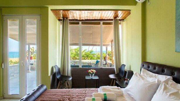 A hotel room with a bed, a small table with a vase of flowers, two chairs, and a view of the ocean through a sliding door.