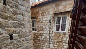 Un estrecho callejón con edificios de piedra, una puerta de madera y una pequeña ventana con una lámpara.