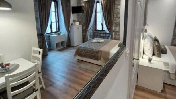 Una habitación de hotel compacta con una cama, un escritorio pequeño, una silla y una mesa de comedor.