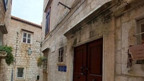 Un estrecho callejón de piedra con una gran puerta de madera y escalones que conducen a un edificio.