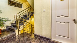 A staircase with a metal railing, a potted plant, and a door with a number plate. - FabHotel Emara Boutique - Near Koramangala (Bengaluru)