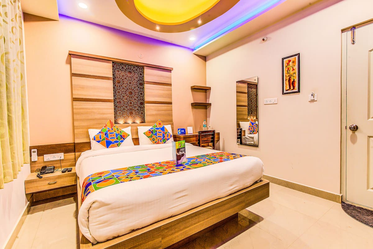 A hotel room with a large bed, wooden headboard, and a decorative wall panel.