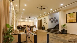 A spacious lobby with a high ceiling, multiple seating areas, and a staircase leading to an upper floor. - FabHotel All In One Saltlake (Barasat)
