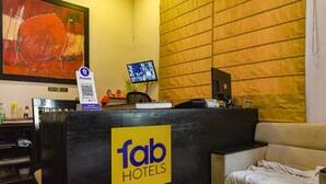 A hotel reception desk with a 'Tab Hotels' sign, a monitor displaying multiple screens, and a 'First Aid Box' label. - FabHotel All In One Saltlake (Barasat)