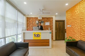 Ein Hotel-Empfangsbereich mit modernem Design, darunter eine Rezeption, eine Uhr und eine Wand mit strukturierter Oberfläche.
