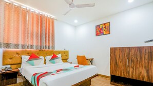 Un dormitorio con cama, armario de madera, ventilador de techo, mesita de noche y un cuadro en la pared.
