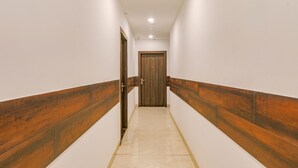 Un pasillo con paredes blancas, paneles de madera a los lados y suelo de baldosas.