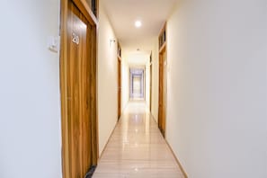 A long, narrow hallway with wooden doors on either side, numbered 20 and 21. - FabHotel Cozy Inn (Mumbai)