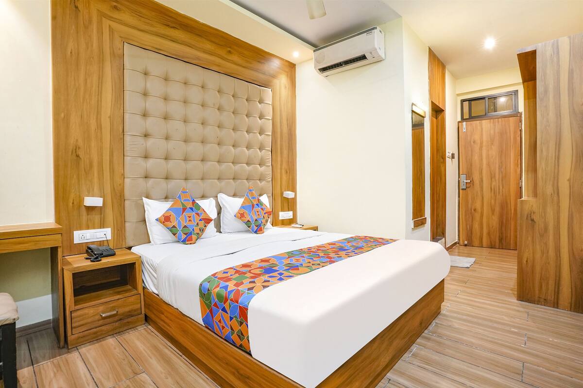 A neatly arranged bedroom with a large bed, wooden headboard, bedside tables, and a wardrobe.