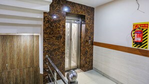 Een lift met een marmeren wand, een brandblusserteken en een handgreep.