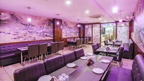 Een restaurant met paarse zitplaatsen, een muurschildering en een modern interieur.