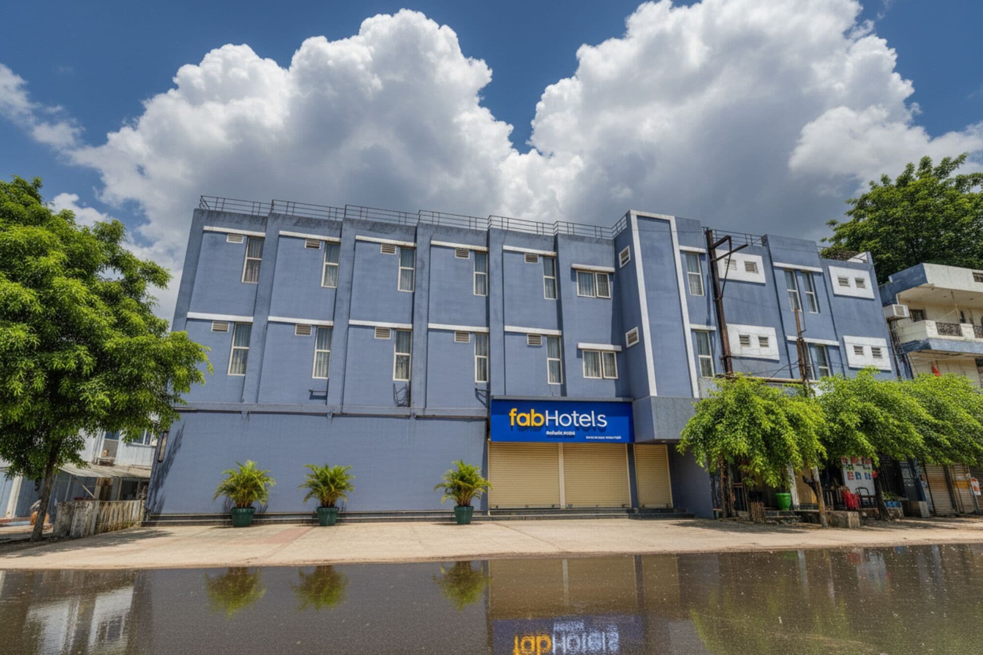 A hotel building with a blue facade, multiple windows, and a 'fabHotels' sign.