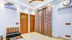 A hotel room with a wooden door labeled 102, a wooden bench, a table with a menu, and a patterned curtain. - Fabhotel Floyd (New Delhi)
