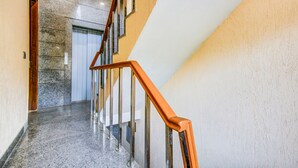 A modern interior with a marble staircase, a wooden handrail, and a clean, polished floor. - Fabhotel Floyd (New Delhi)