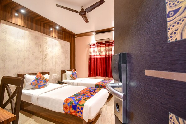 A hotel room with two beds, a ceiling fan, an air conditioning unit, and a television.