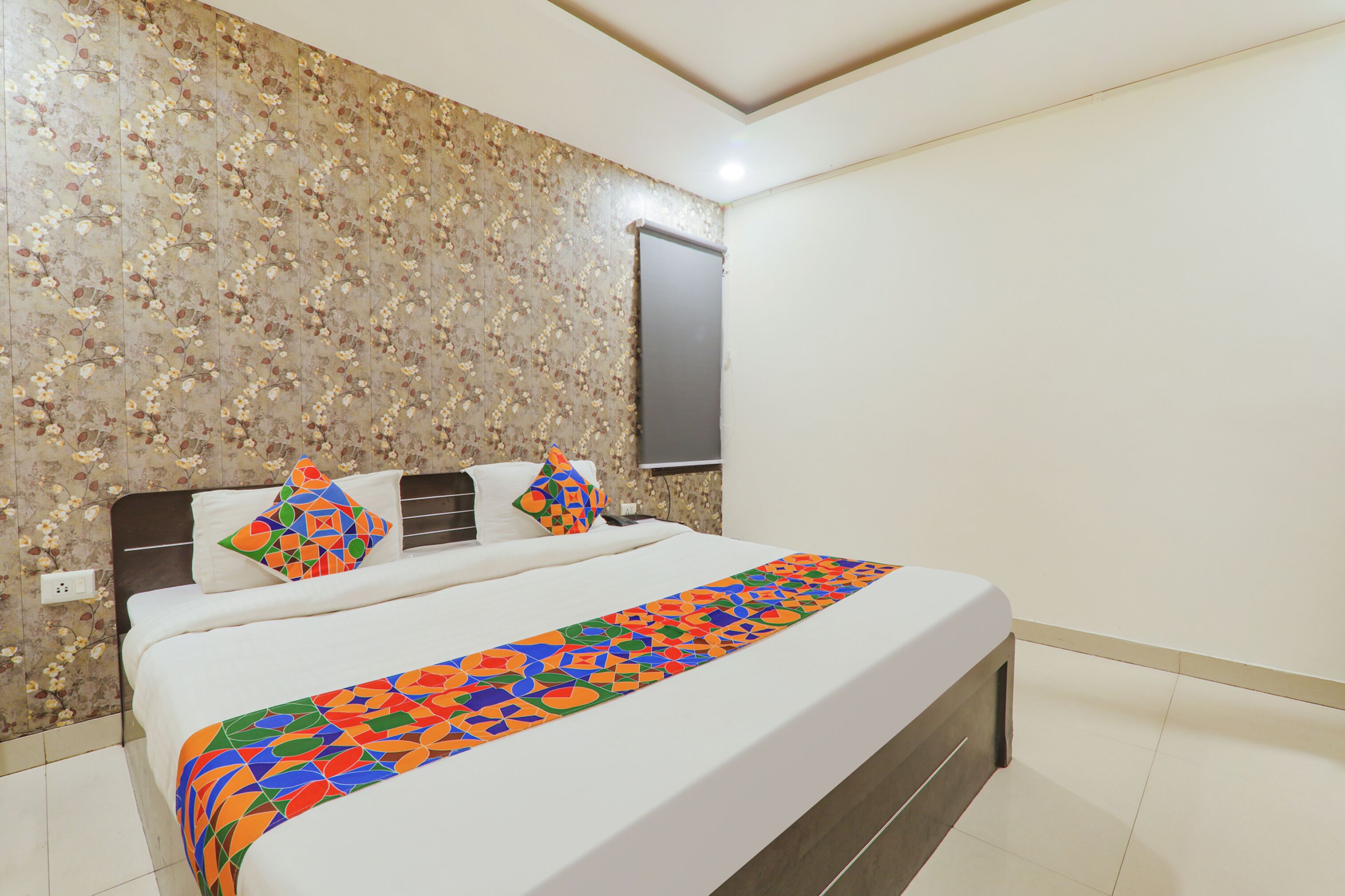 Uma cama bem arrumada com um edredom colorido, cabeceira e duas almofadas.