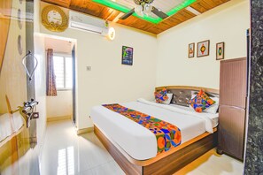 Quarto com cama, cabeceira de madeira, geladeira e relógio de parede.