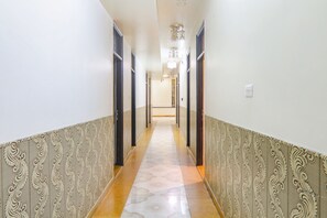 Un pasillo con paredes de diseño y suelo de baldosas, que conduce a una puerta al final.