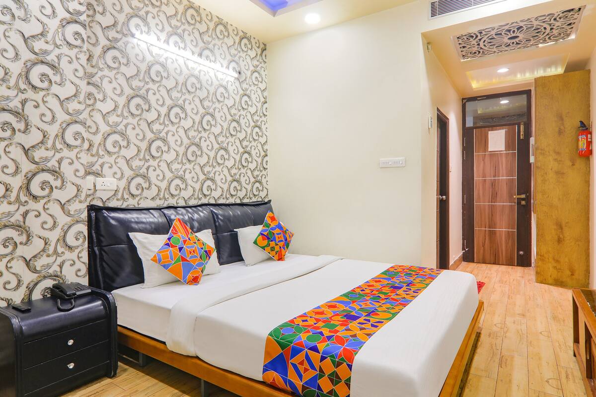 Una habitación de hotel con una cama, una mesita de noche, una maleta y una puerta de madera.