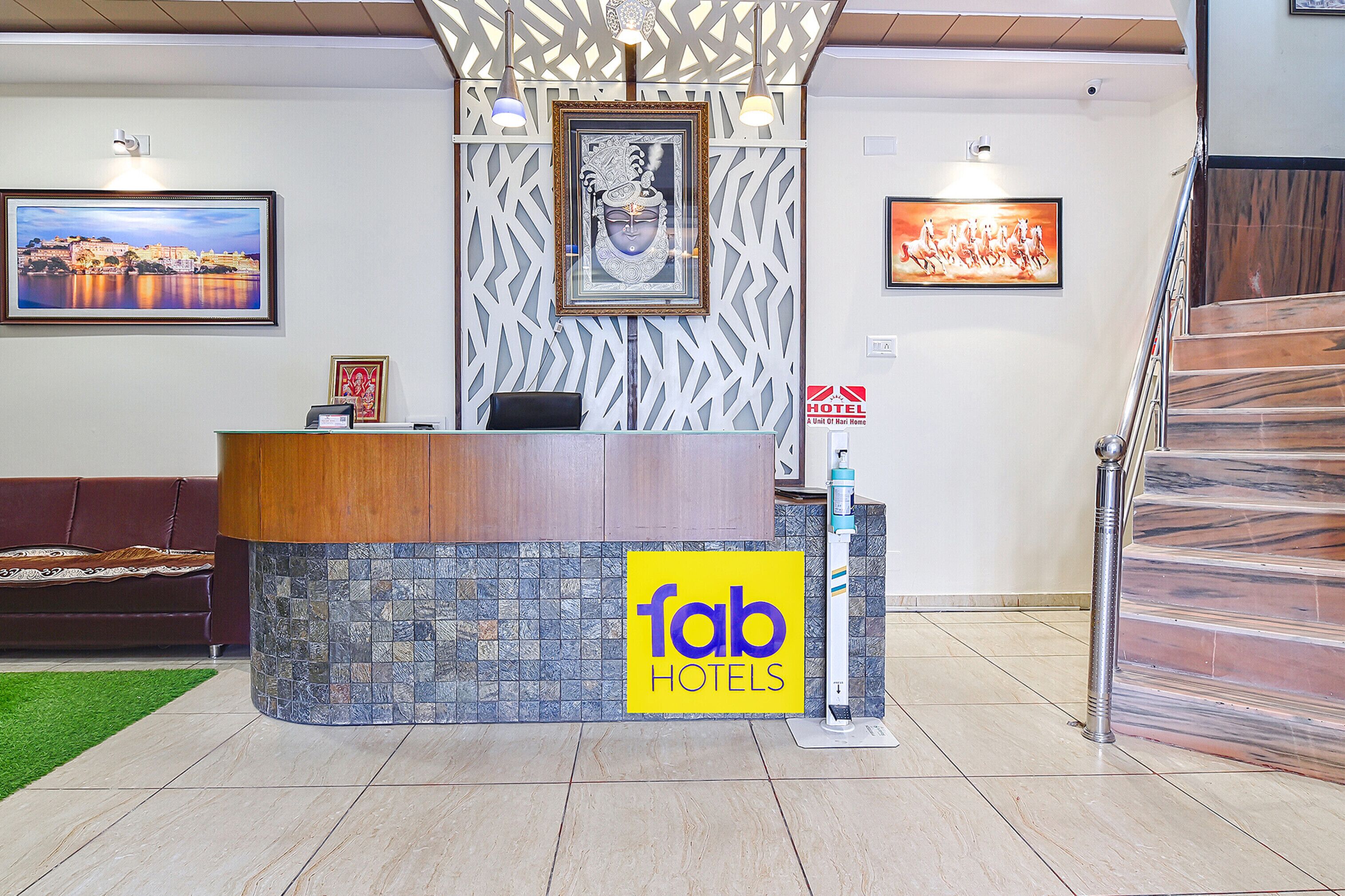 Una recepción con un letrero de 'fab hotels', una obra de arte enmarcada encima y una escalera a la derecha.