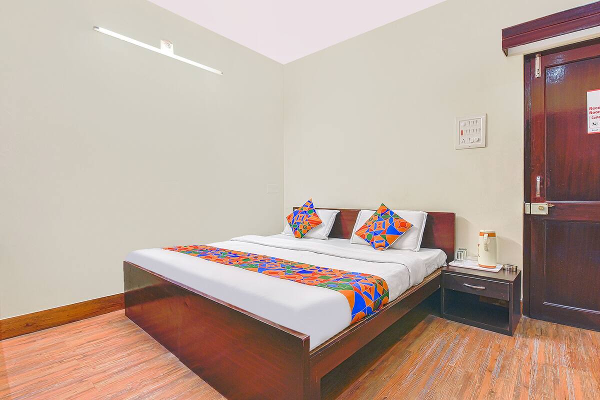 A hotel room with a bed, bedside table, and a door.