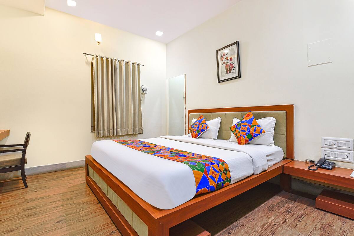 A hotel room with a wooden bed, a desk with a phone, and a chair.