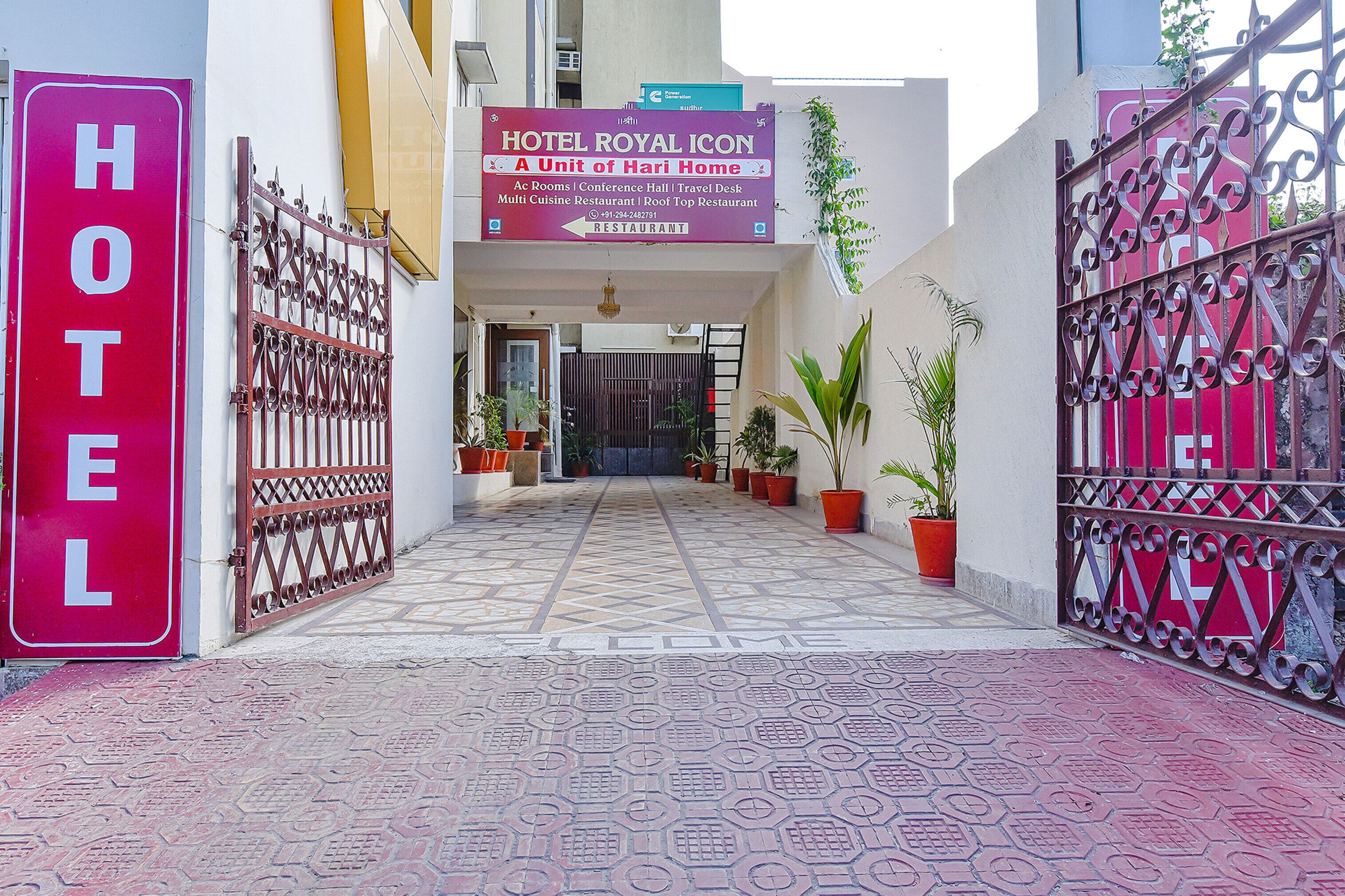 A hotel entrance with a sign indicating it is a unit of Hari Home, featuring amenities like conference hall, travel desk, and multi-cuisine restaurant.