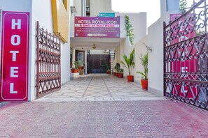 L’entrée d’un hôtel, avec une enseigne indiquant qu’il fait partie du groupe Hari Home, et qui propose des équipements tels qu’une salle de conférence, un service d’assistance aux voyageurs et un restaurant proposant une cuisine variée.