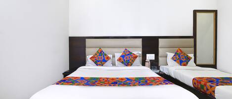 Quarto de hotel com uma cama grande, duas mesinhas de cabeceira, um criado-mudo, um espelho e uma janela.